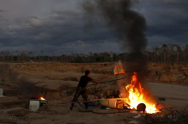 A Peruvian police officer burns equipment used by illegal miners during an operation to destroy illegal gold mining camps in a zone known as Mega 14, in the southern Amazon region of Madre de Dios July 13, 2015. (Photo by Janine Costa/Reuters)