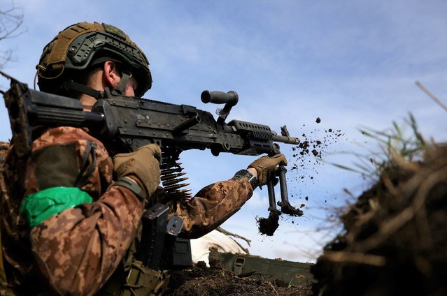 Ukrainian service member, Naza, 21, commander from 28th mechanised brigade repositions his machine gun during a fire exchange at the frontline, amid Russia's attack on Ukraine in the region of Bakhmut, Ukraine on April 5, 2023. (Photo by Kai Pfaffenbach/Reuters)