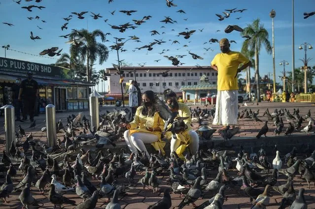 Hindu devotees feed pigeons outside a temple in Batu Caves, ahead of the Thaipusam festival, on the outskirts of Kuala Lumpur on January 17, 2022. (Photo by Arif Kartono/AFP Photo)