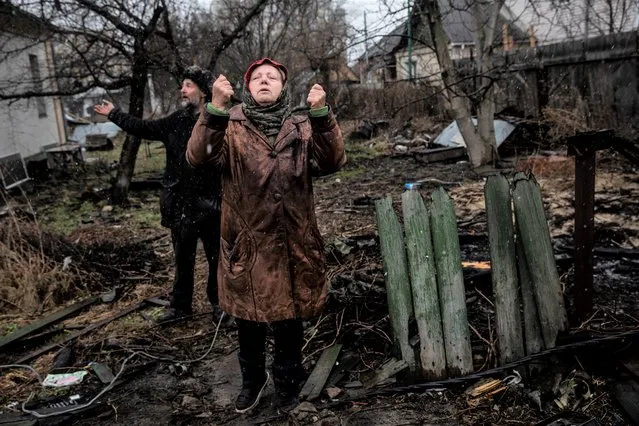 Larisa Savenko 72, stands outside her damaged home with Andriy Leshbon in war torn Bucha, Ukraine where destroyed Russian tanks, armored vehicles and other equipment litter the road where she lives on April 3,2022.She has stayed in her home since the Russians arrived to her neighborhood on February 27th. “A Russian APC was parked at my garden for 3 days (from march 5 to 7). Five gunmen entered my house, they looked at our documents and took our phones away. The Russian told us that we are lucky to have them, because other Russian troops would have already shot them. The Russians kicked out my neighbors out of their home at night, and lived in their house. We had to stay in our stable for a couple of nights with 3 dogs, 5 cats and 3 people. We were not allowed to start a fire to heat ourselves. The gunfire did not stop for a moment”. (Photo by Heidi Levine/The Washington Post)