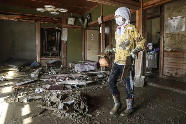 A boy cleans a house devastated by Typhoon Hagibis, in Nagano, central Japan Wednesday, October 16, 2019. The typhoon hit Japan's main island on Saturday with strong winds and historic rainfall that caused more than 200 rivers to overflow, leaving thousands of homes flooded, damaged or without power. (Photo by Koki Sengoku/Kyodo News via AP Photo)