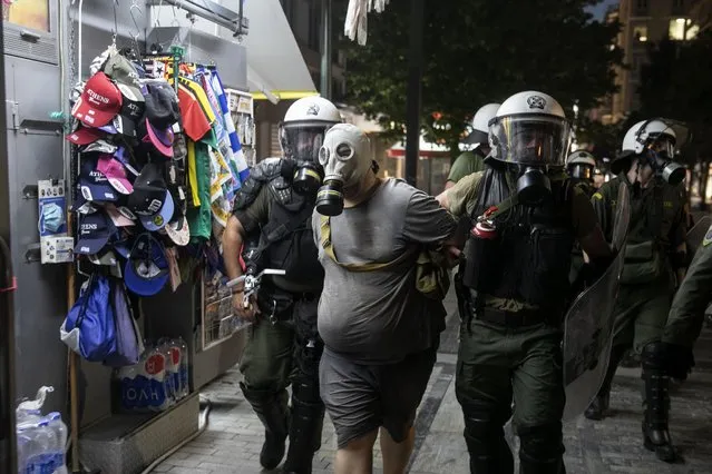 Police detain a masked anti-vaccine protester during clashes around central Syntagma square, in Athens, Greece, Sunday, August 29, 2021. Police used tear gas to disperse thousands of protesters opposing government's plans for mandatory vaccination and new testing requirements and attendance restrictions on people who aren't vaccinated against COVID-19. (Photo by Yorgos Karahalis/AP Photo)