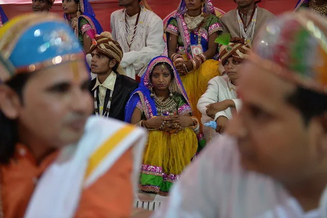 Indian brides and grooms wait for the start of a mass wedding in New Delhi on June 15, 2014. Some 92 low-income and disabled couples tied the knot in a free mass wedding ceremony organised by the non-profit organisation Narayan Sewa Sansthan. (Photo by Chandan Khanna/AFP Photo)