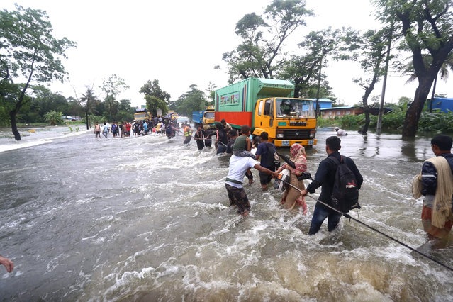 People wade through flood waters in Feni on August 22, 2024. Floods triggered by torrential rains have swamped a swath of low-lying Bangladesh, disaster officials said on August 22, adding to the new government's challenges after weeks of political turmoil. (Photo by AFP Photo/Stringer)