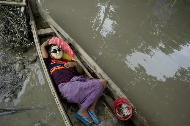 A resident rests in a boat next to floodwaters in Kalay, upper Myanmar's Sagaing region on August 3, 2015. Relentless monsoon rains have triggered flash floods and landslides, destroying thousands of houses, farmland, bridges and roads – with fast-flowing waters hampering relief efforts. (Photo by Ye Aung Thu/AFP Photo)