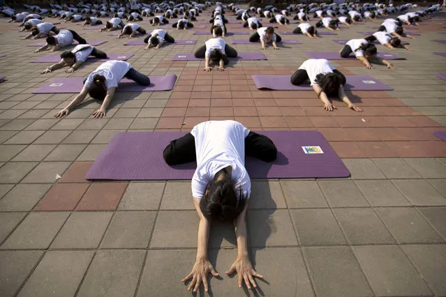 Participants strike a pose during a group yoga session at a park in Beijing, Saturday, June 18, 2016. Several hundred Chinese yoga enthusiasts participated in a mass yoga session on Saturday morning to mark International Yoga Day, which falls on June 21. (Photo by Mark Schiefelbein/AP Photo)