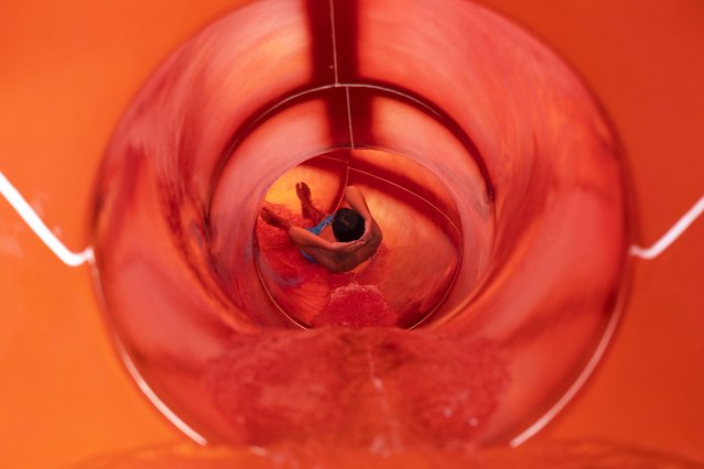 A youth enjoys a water slide at a water park of Spata town, east of Athens, Greece, Sunday, July 23, 2023. Heat in Greece is expected to grow worse during the weekend, approaching 44 Celsius (111 Fahrenheit) and the country will face one more heatwave episode by the end of July. (Photo by Yorgos Karahalis/AP Photo)