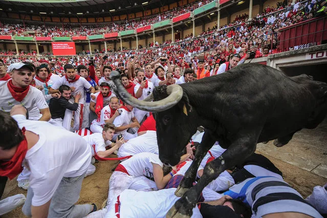 A cow jumps over revelers on the bull ring at the San Fermin festival, in Pamplona, Spain, Tuesday, July 8, 2014. Revelers from around the world in Pamplona take part in an eight-day event of the running of the bulls glorified by Ernest Hemingway's 1926 novel “The Sun Also Rises”. (Photo by Alvaro Barrientos/AP Photo)