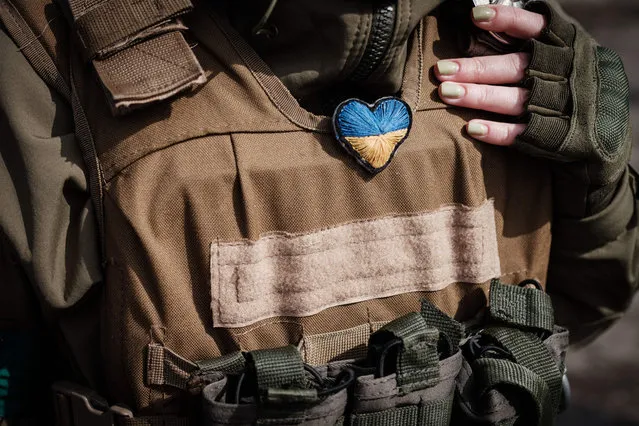 A female Ukrainian soldier puts a heart-shaped and Ukrainian flag coloured accessary given by a child at a checkpoint in Bakhmut, eastern Ukraine, on April 23, 2022 amid the Russian invasion of Ukraine. (Photo by Yasuyoshi Chiba/AFP Photo)
