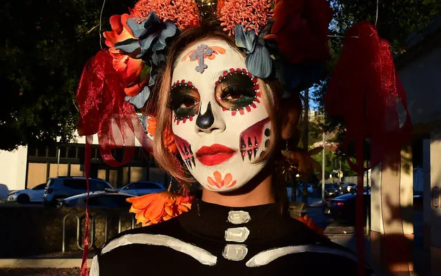 Brittany Bautista gets dressed up for a Dia de los Muertos (Day of the Dead) procession hosted by the Southwest Voter Registration Education Project (SVREP) on October 26, 2021 in Los Angeles. SVREP is the oldest Latino voter registration non-profit in the US empowering Latinos to mobilize voters. (Photo by Frederic J. Brown/AFP Photo)