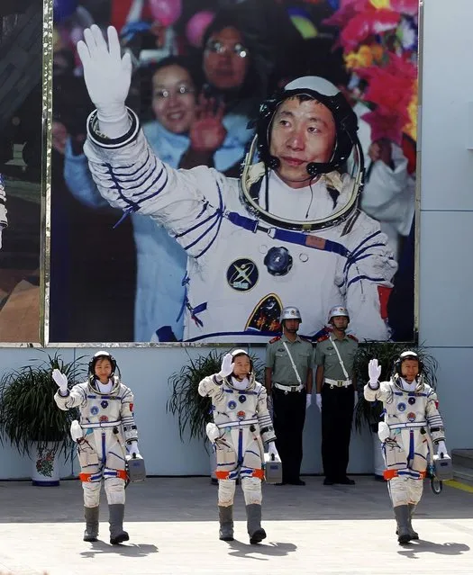 China's astronauts from left., Liu Yang, Jing Haipeng and Liu Wang wave and walk before a giant portrait of China's first astronaut Yang Liwei, as they depart for the Shenzhou 9 spacecraft rocket launch pad at the Jiuquan Satellite Launch Center in Jiuquan, China, Saturday, June 16, 2012