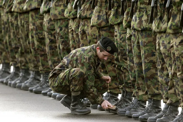 A soldier of the Swiss federal army polishes the boots of his comrades before a welcoming ceremony at Zurich's-Kloten airpor. (Photo by Arnd Wiegmann/Reuters)