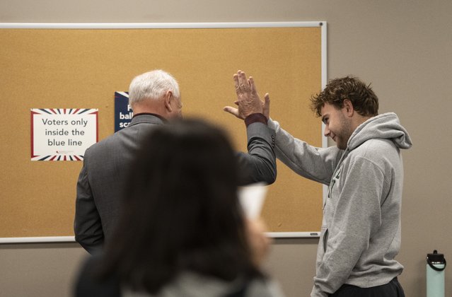 Democratic vice presidential nominee Minnesota Gov. Tim Walz, left, high-fives his son, Gus Walz, a first-time voter, as they cast their ballots during early voting at the Ramsey County Elections office in St. Paul, Minn., Wednesday, October 23, 2024. (Photo by Renée Jones Schneider/Star Tribune via AP Photo)