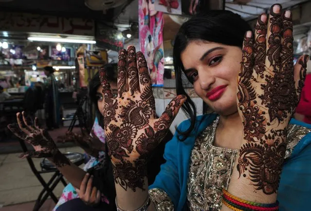 A Pakistani woman displays her hands decorated with traditional henna design at a mall ahead of the Muslim festivities of Eid al-Fitr, in Karachi on July 26, 2014. Muslims around the world are preparing to celebrate the Eid al-Fitr holiday, which marks the end of the fasting month of Ramadan. (Photo by Asif Hassan/AFP Photo)