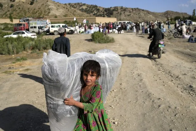 Afghan girl carries a donated matrace after an earthquake in Gayan village, in Paktika province, Afghanistan, Friday, June 24, 2022. (Photo by Ebrahim Nooroozi/AP Photo)