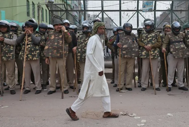 A Muslim man walks past policemen standing guard next to a mosque in a riot affected area following clashes between people demonstrating for and against a new citizenship law in New Delhi, India, February 28, 2020. (Photo by Rupak De Chowdhuri/Reuters)