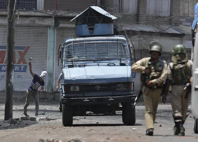 A Kashmiri Muslim protester throws a stone at Indian paramilitary soldiers in Srinagar, Indian controlled Kashmir, Sunday, July 10, 2016. Indian troops and protesters clashed in several parts of the state despite a curfew imposed in the Himalayan region following the killing of a popular rebel commander. (Photo by Mukhtar Khan/AP Photo)