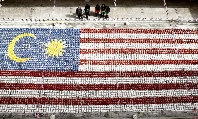 Students watch a giant Malaysian national flag made of coconut shells at Selayang in Kuala Lumpur, Malaysia, Monday, August 28, 2017. Students and Malaysia Welfare Department collaborated to made the giant flag with over 5,000 coconut shells in conjunction of Malaysia's 60th Independence Day on Aug. 31. (Photo by Daniel Chan/AP Photo)