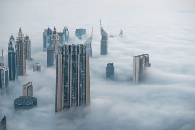 This breathtaking view from the world's tallest building shows a thick blanket of smoggy fog smother Dubai. The mist almost completely covers the huge sculptures which dominate the skyline. And the spectacular view from the Burj Khalifa – standing at a staggering 828 metres tall – shows the city engulfed by the thick fog. And the smoggy fog reaches heights of up to 400 metres as it rises above the impressive skyscrapers in Dubai. (Photo by Bjoern Lauen/Solent News/SIPA Press)