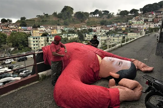 Supporters of Venezuela's late President Hugo Chavez bring down an inflatable doll of Chavez during a commemoration of what would have been the leader's 68th birthday, at the 23 de Enero neighborhood in Caracas, Venezuela, Thursday, July 28, 2022. (Photo by Ariana Cubillos/AP Photo)