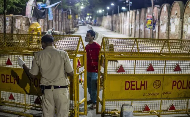 A man pleads before and Indian police officer to allow him to cross the barricade erected by Indian police on a deserted road to enforce a lockdown during night, as nationwide lockdown continues over the highly contagious coronavirus (COVID-19) on March 29, 2020 in Ghaziabad, on the outskirts New Delhi, India. India is under a 21-day lockdown to fight the spread of the virus while security personnel on the roads are enforcing the restrictions in many cases by using force, the workers of country's unorganized sector are bearing the brunt of the curfew-like situation. The lockdown has already disproportionately hurt marginalized communities due to loss of livelihood and lack of food, shelter, health, and other basic needs. The lockdown has left tens of thousands of out-of-work migrant workers stranded, with rail and bus services shut down. According to international labour organisations 90 percent of India's workforce is employed in the informal sector and most do not have access to pensions, sick leave, paid leave or any kind of insurance. The closing of state borders have caused disruption in the supply of essential goods, leading to inflation and fear of shortages. Reports on Thursday said that Prime Minister Narendra Modi's government is preparing a massive bailout for the underprivileged sections of the country and will hand over the aid through direct cash transfers. (Photo by Yawar Nazir/Getty Images)