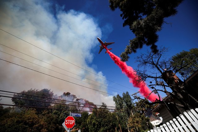 A plane makes a drop as smoke billows from the Palisades Fire at the Mandeville Canyon, in Los Angeles, California, U.S., January 11, 2025. (Photo by Carlos Barria/Reuters)