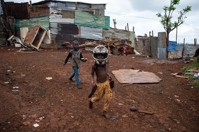 A boy with a motobike helmet walks amidst destroyed houses in shanty town of Cavani south district damaged by the cyclone Chido in the city of Mamoudzou, on the French Indian Ocean territory of Mayotte, on January 2, 2025. The most devastating cyclone to hit Mayotte in 90 years caused colossal damage on December 14, 2024 in France's poorest department. (Photo by Julien de Rosa/AFP Photo)