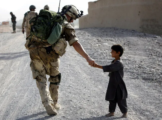 A Canadian soldier shakes hands with an Afghan boy during a joint patrol with Afghan National Army troops near Panjwaii village, Kandahar province, southern Afghanistan, July 13, 2007. (Photo by Finbarr O'Reilly/Reuters)