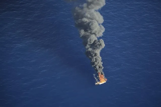 In this handout photo released by German non-governmental organization Sea-Watch on Tuesday, October 25, 2022, an empty rubber boat used by migrants attempting to cross the Mediterranean Sea to Europe is seen on fire after being intercepted by a Libyan coast guard ship in international waters. (Photo by Fiona Alihosi/Sea-Watch via AP Photo)