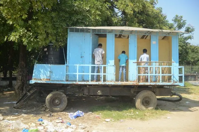 Indian youths use a mobile toilet facility at a park in Hyderabad, India on November 10, 2017. (Photo by Noah Seelam/AFP Photo)