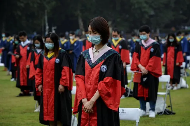 Graduating university students wearing face masks observe a moment of silence in tribute to victims of the coronavirus, during a graduation ceremony held at Wuhan University in Wuhan, Hubei province, China on June 20, 2020. (Photo by China Daily via Reuters)