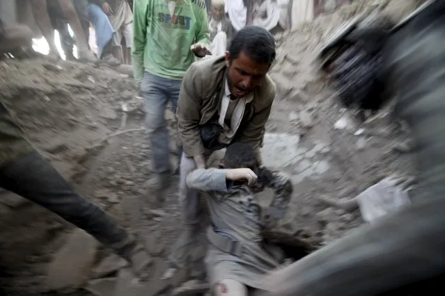A man carries a body from the rubble of a house destroyed by an air strike at the old quarter of Yemen's capital Sanaa, September 19, 2015. (Photo by Mohamed al-Sayaghi/Reuters)