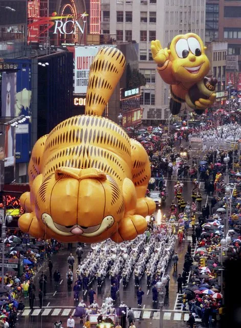 Balloons of “Garfield”, and the “Honey Nut Cheerios Bee”, right, participate in the 73rd annual Macy's Thanksgiving Day Parade Thursday, November 25, 1999, in New York's Times Square. (Photo by Suzanne Plunkett/AP Photo)