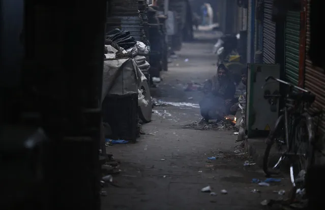 People warm themselves by a fire at a market on a cold winter morning in the old quarters of Delhi January 6, 2013. (Photo by Adnan Abidi/Reuters)