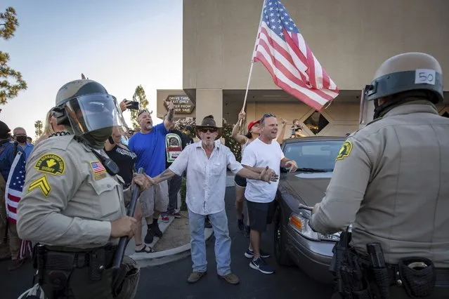 Supporters of President Donald Trump yell at counter protesters as police escort them away from the scene Saturday, August 1, 2020, in Yucaipa, Calif. A clash between locals erupted after Black Lives Matter protesters interrupted a pro-Trump demonstration. (Photo by Christian Monterrosa/AP Photo)