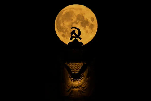 The full moon is pictured behind the Soviet symbol of hammer and sickle atop a building in Moscow late on August 3, 2020. (Photo by Kirill Kudryavtsev/AFP Photo)