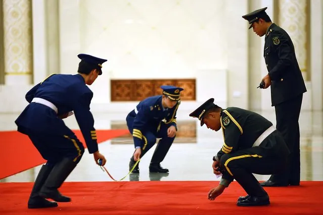 Officers mark on the red carpet where an honour guard should stand before a welcoming ceremony for Ukraine's President Viktor Yanukovych in Beijing, China. (Photo by Feng Li)