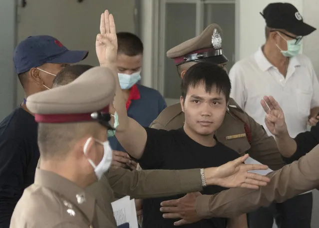 Tattep Ruangprapaikitseree raises a three-finger salute, a symbol of resistance, as he leaves the Samranrat police station for a court appearance in Bangkok, Thailand, Wednesday, August 26, 2020. Tattep is among the leaders of a student movement organizing protests to demand that the government of Prime Minister Prayuth Chan-ocha call new elections, the constitution be amended to be more democratic and harassment of critics of the government cease. The police have arrested several other members of the movement on various charges, including sedition. (Photo by Sakchai Lalit/AP Photo)