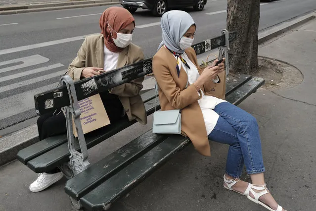 Women check their phone wearing a protective face masks as a precaution against the coronavirus in Paris, Saturday, September 5, 2020. (Photo by Francois Mori/AP Photo)