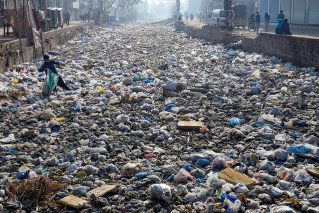 A waste picker scouts for recyclable junk from a sewage drain used as a garbage dump, at a slum area in Lahore on March 4, 2024. (Photo by Syed Murtaza/AFP Photo)