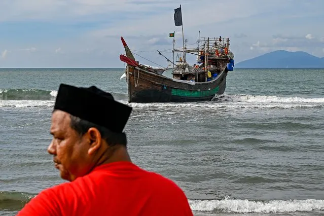 A man stands near a boat used by Rohingya refugees to arrive in Lamnga beach, Aceh province on January 8, 2023. A wooden boat carrying nearly 200 Rohingya refugees, a majority of them women and children, landed on Indonesia's western coast on January 8, police said. (Photo by Chaideer Mahyuddin/AFP Photo)