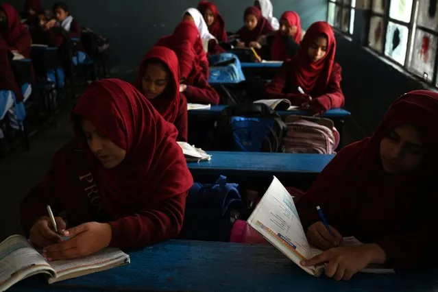 Students attend a class at a government high secondary school during a nationwide power outage in Rawalpindi on January 23, 2023. A massive power breakdown in Pakistan on January 23 affected most of the country's more than 220 million people, including in the mega cities of Karachi and Lahore. (Photo by Aamir Qureshi/AFP Photo)