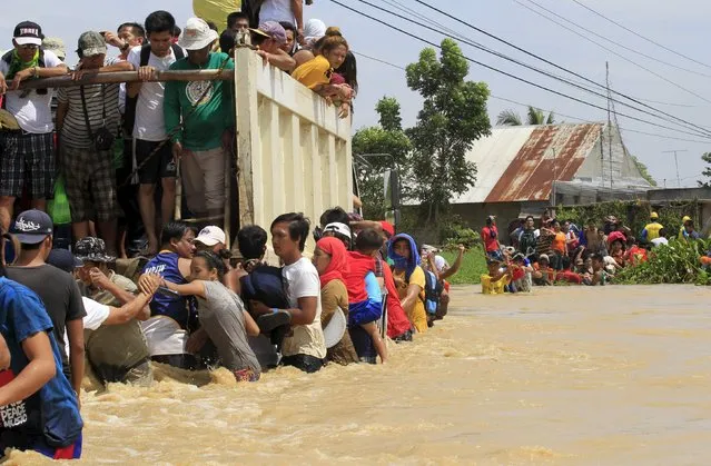 Residents hold on a rope while crossing floodwaters brought by typhoon Koppu that battered Candaba town, Pampanga province, north of Manila October 20, 2015. (Photo by Romeo Ranoco/Reuters)