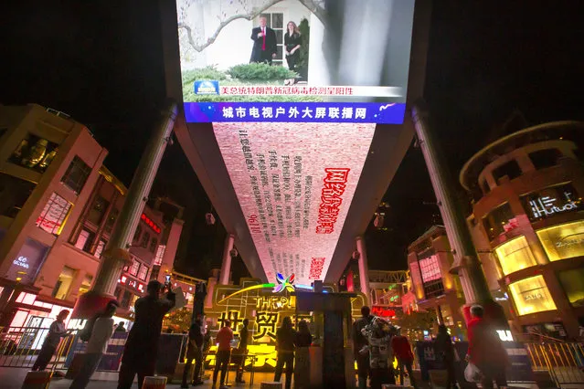 People watch a large screen showing President Donald Trump and First Lady Melania Trump during a news report from Chinese state television about Trump testing positive for the coronavirus in Beijing, Friday, October 2, 2020. Trump said early Friday that he and first lady Melania Trump have tested positive for the coronavirus, a stunning announcement that plunges the country deeper into uncertainty just a month before the presidential election. (Photo by Mark Schiefelbein/AP Photo)