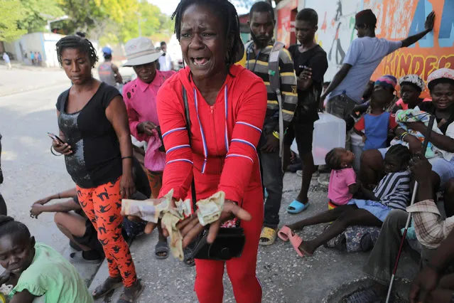 Rose Delpe cries as she shows money next to people displaced by gang war violence in Cite Soleil resting on the streets of Delmas neighborhood after leaving Hugo Chaves square in Port-au-Prince, Haiti on November 19, 2022. (Photo by Ralph Tedy Erol/Reuters)