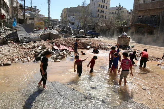 Children play with water from a burst water pipe at a site hit yesterday by an air strike in Aleppo's rebel-controlled al-Mashad neighbourhood, Syria, September 30, 2016. (Photo by Abdalrhman Ismail/Reuters)