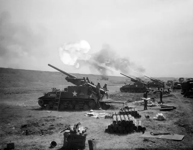 Smoke and flame belch from muzzles of the big 155mm U.S. army guns on the western Korean front as allied artillery poured a continuous round of fire into enemy positions, May 5, 1951. (Photo by AP Photo)