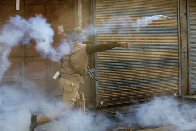 An Indian policeman throws back an exploded tear gas shell towards Kashmiri Muslim protesters during a protest in Srinagar, Indian controlled Kashmir, Friday, October 30, 2015. Police fired teargas and rubber bullets to disperse Kashmiris who gathered after Friday afternoon prayers to protest against the killing of Abu Qasim, a Pakistani national and operations chief of the Lashkar-e-Taiba militant group. (Photo by Dar Yasin/AP Photo)