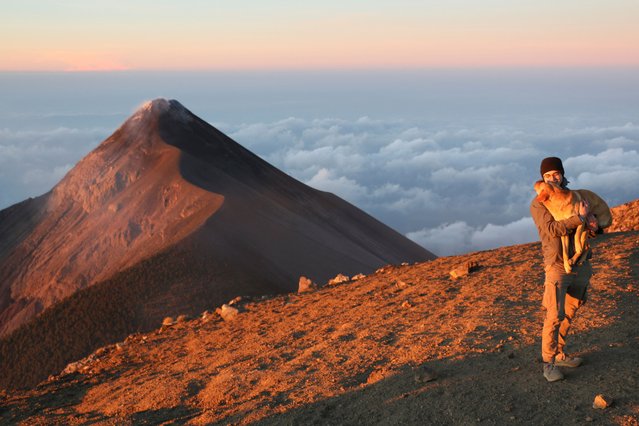 A hiker poses with a dog in front of the Fuego Volcano while standing at the Acatenango Volcano, near Aldea La Soledad, Guatemala on March 15, 2025. (Photo by Aldo Nicolai/Reuters)