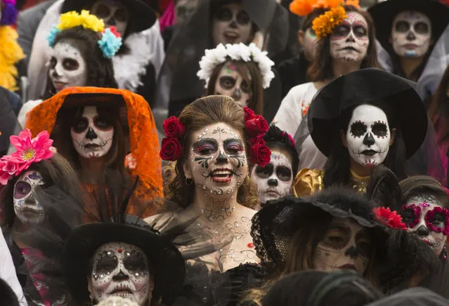People dressed as "Catrinas" gather for a group photo as they commemorate Day of the Dead, a holiday that honors the deceased, during a Catrina Fest in Mexico City, Sunday, November 1, 2015. The figure of a skeleton wearing an elegant broad-brimmed hat was first done as a satirical engraving by artist Jose Guadalupe Posada sometime between 1910 and his death in 1913. (Photo by Esteban Felix/AP Photo)